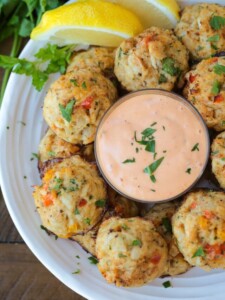 crab balls with dipping sauce on plate with lemons