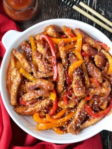 pork stir fry in a bowl with sauce and chop sticks