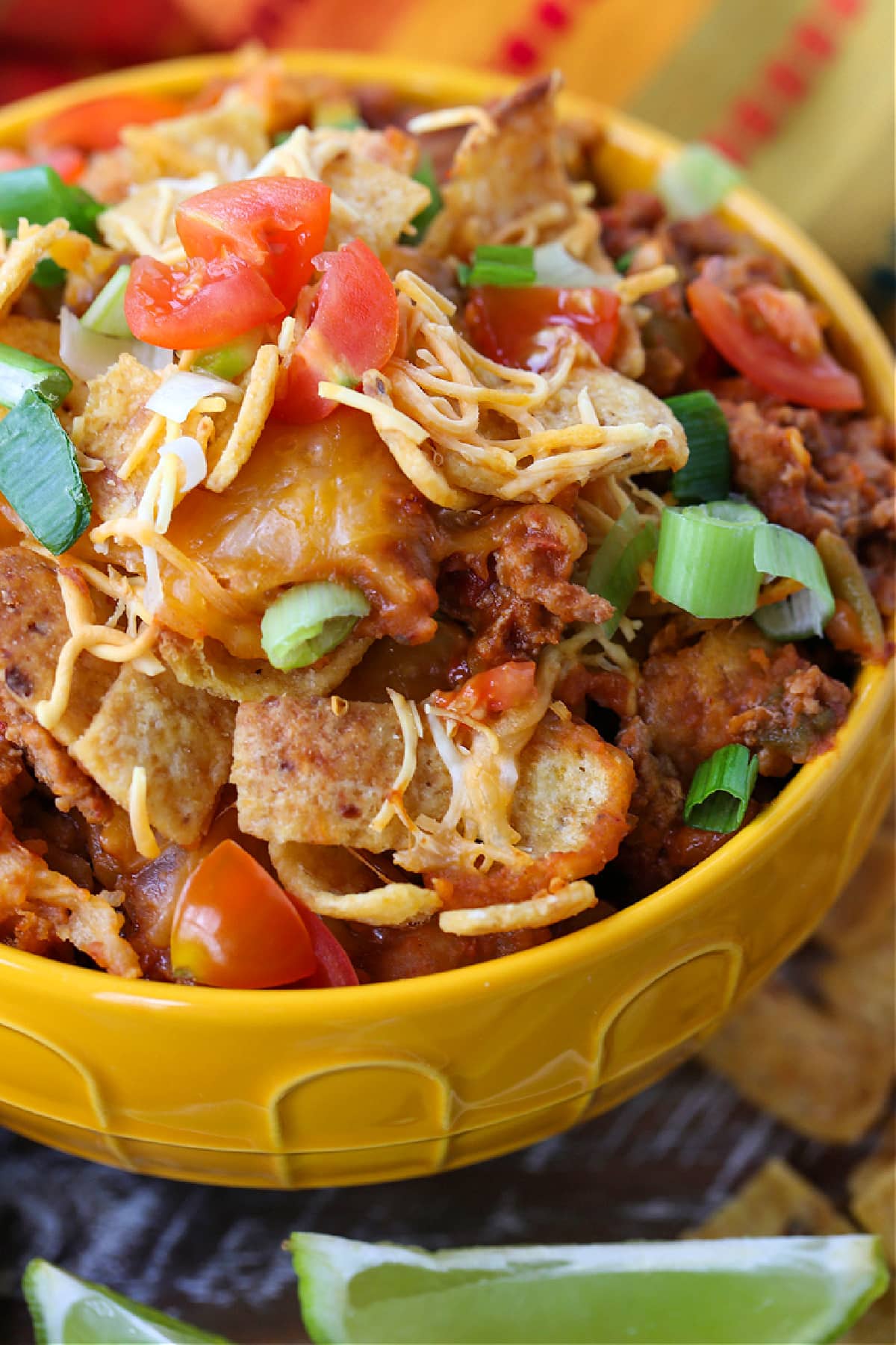 Kids and adults love this Frito Pie Recipe! A ground beef and bean casserole topped with crunchy Fritos corn chips and tons of cheese! ground beef and cheese casserole with fritos in yellow bowl