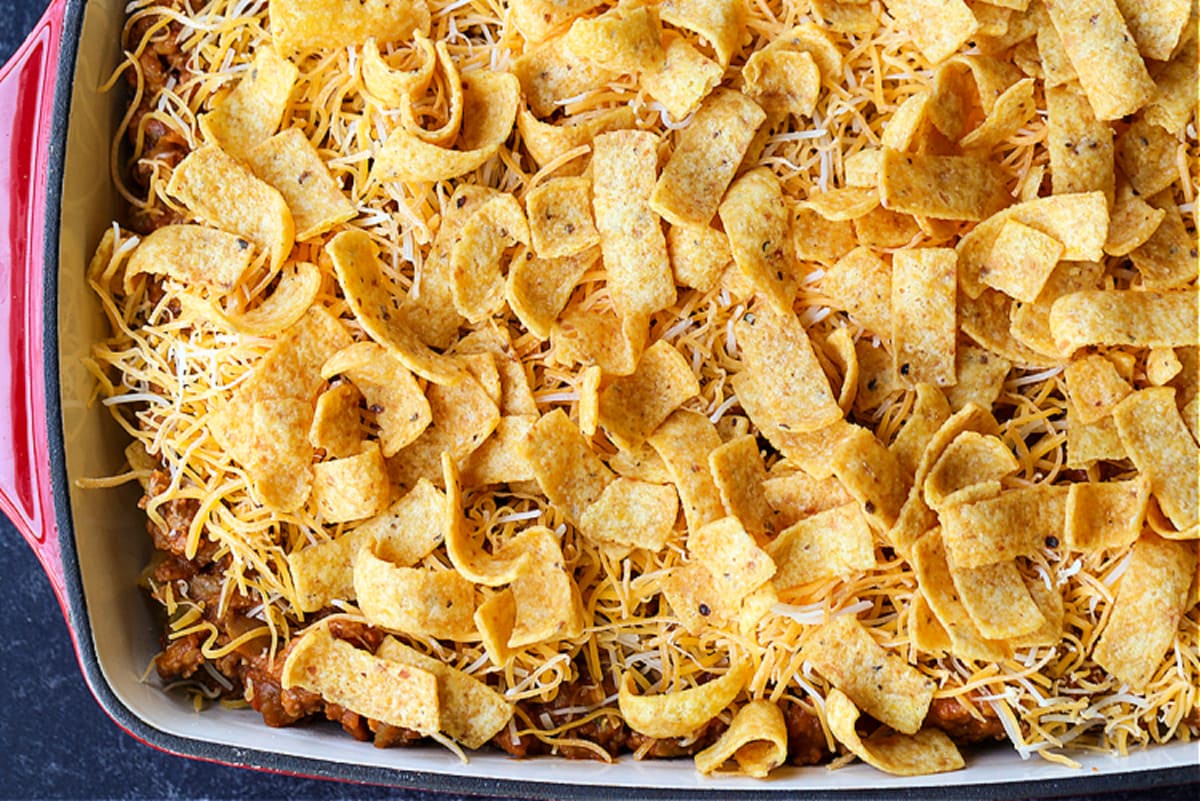 Kids and adults love this Frito Pie Recipe! A ground beef and bean casserole topped with crunchy Fritos corn chips and tons of cheese! fritos on top of cheese and ground beef casserole