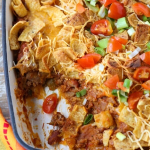 casserole with ground beef, cheese and Fritos in a baking dish with scoop removed