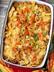 Frito Pie casserole on a wood board with napkin