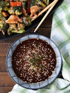 homemade stir fry sauce in a bowl with napkin and chicken and broccoli in background