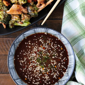 homemade stir fry sauce in a bowl with napkin and chicken and broccoli in background