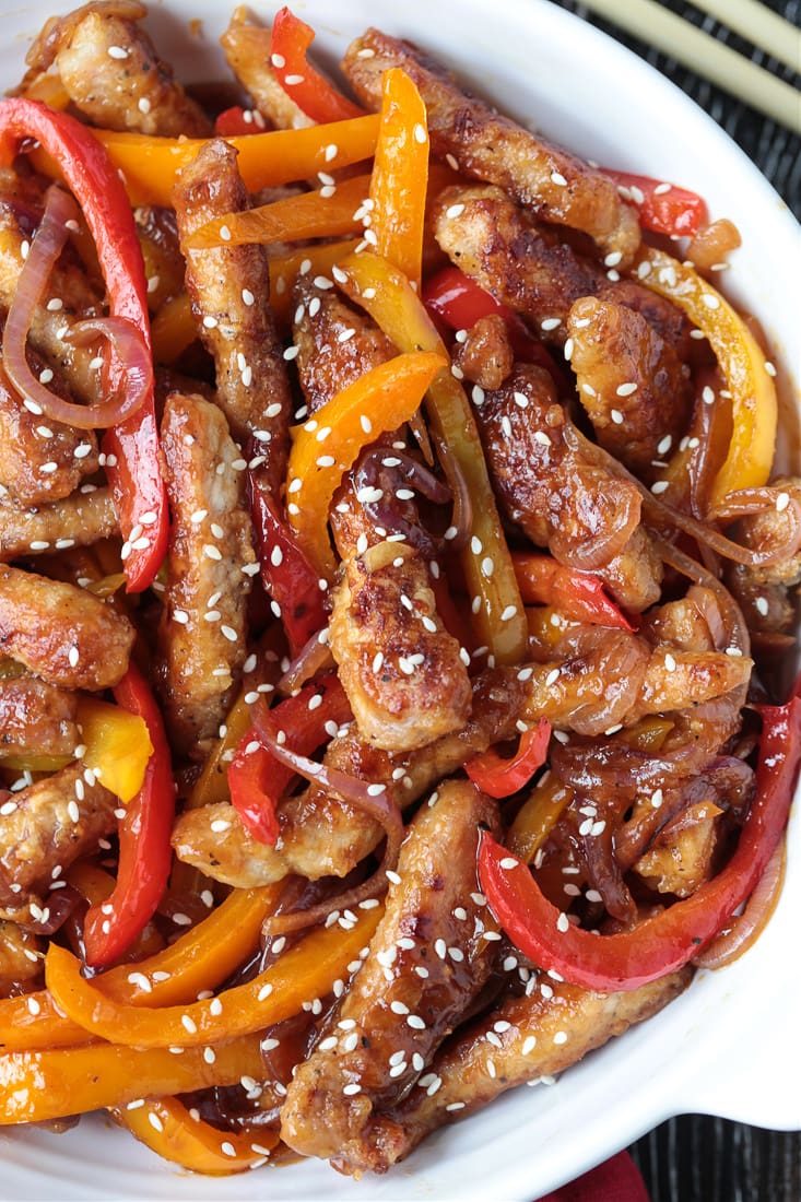 Our Pork Stir Fry Recipe is perfect for weeknight meals. Crispy, tender pork with crunchy vegetables and our famous stir fry sauce. pork stir fry in a bowl topped with sesame seeds