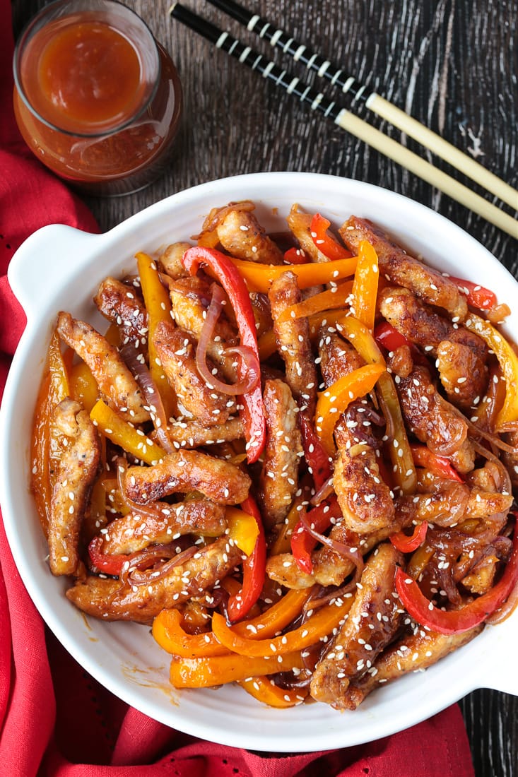 Our Pork Stir Fry Recipe is perfect for weeknight meals. Crispy, tender pork with crunchy vegetables and our famous stir fry sauce. pork stir fry in a bowl with sauce and chop sticks