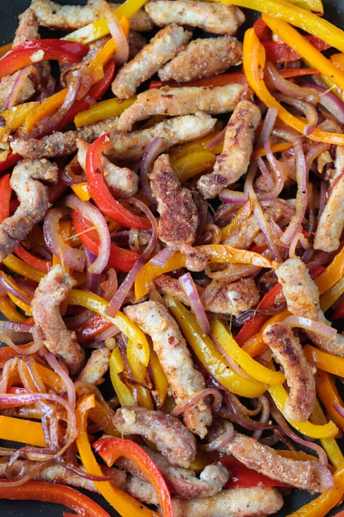 Our Pork Stir Fry Recipe is perfect for weeknight meals. Crispy, tender pork with crunchy vegetables and our famous stir fry sauce. strips of pork and vegetables in a wok