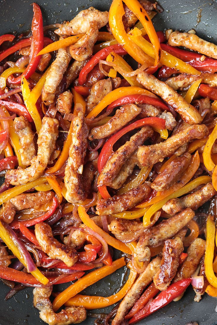 pork strips in a wok with peppers and onions