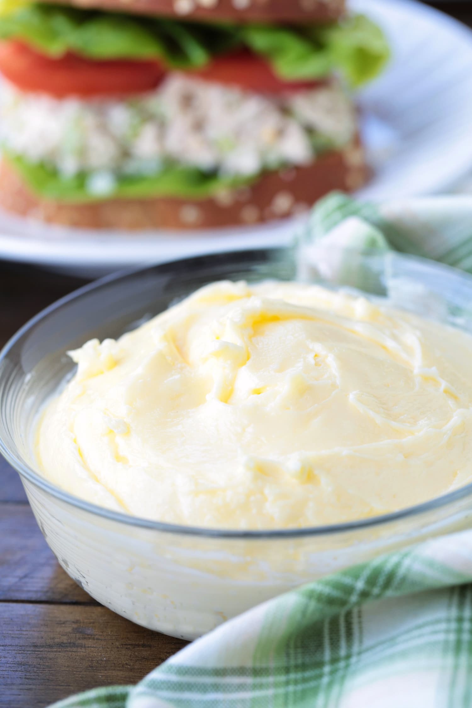 homemade mayonnaise in a bowl in front of sandwich