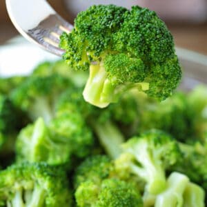 broccoli floret on fork over bowl of broccoli