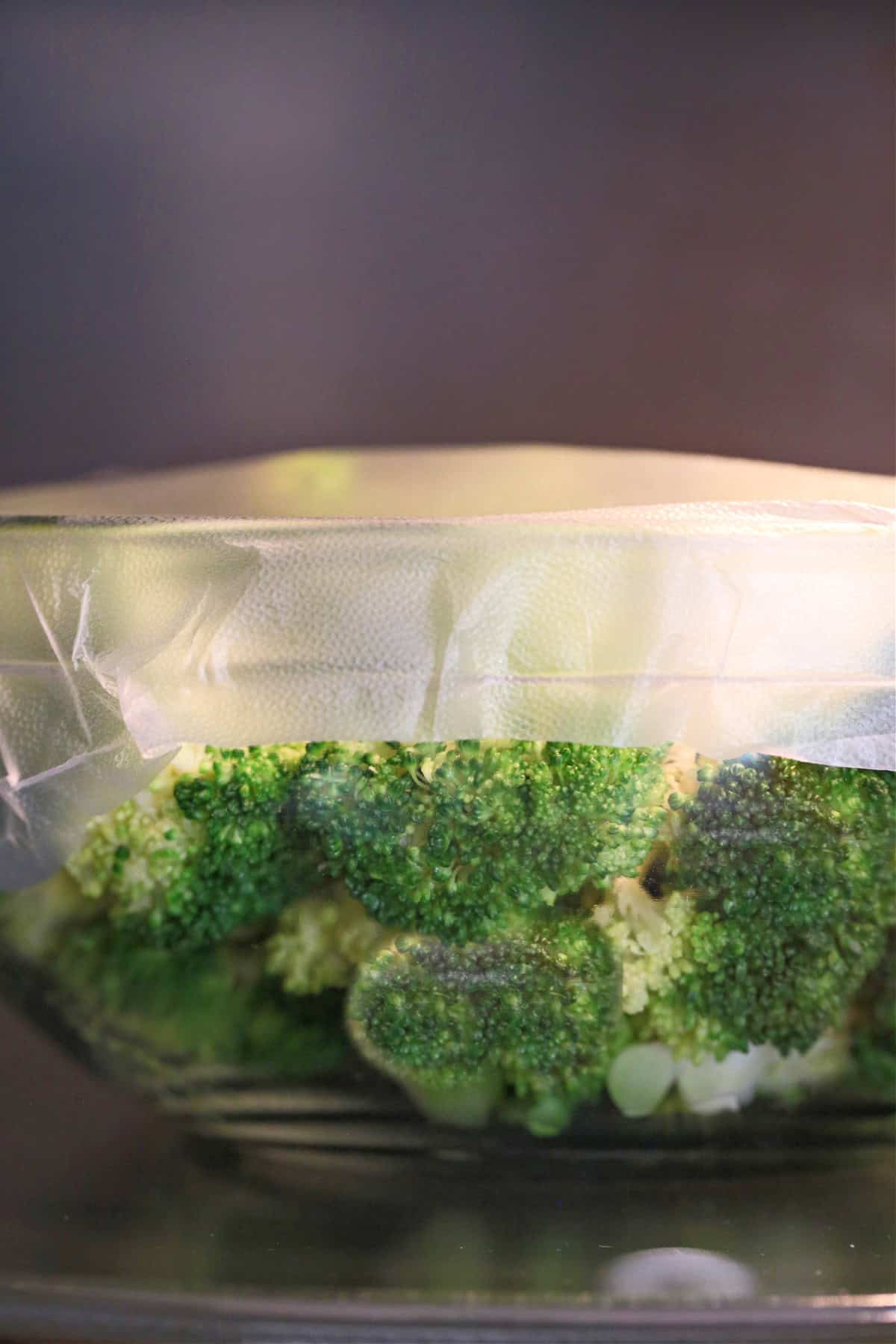 bowl with broccoli covered with plastic wrap