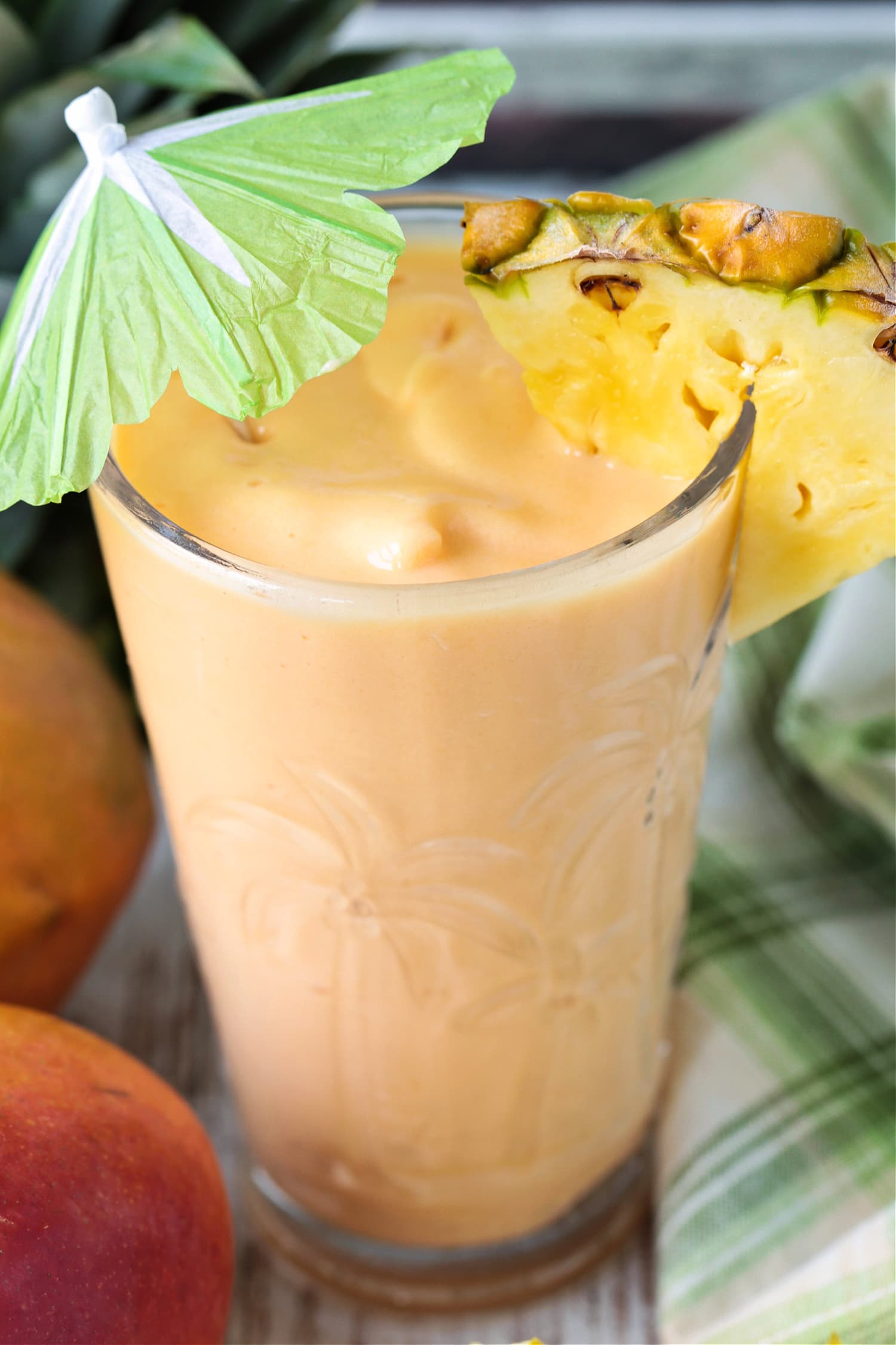 mango smoothie with pineapple garnish and umbrella
