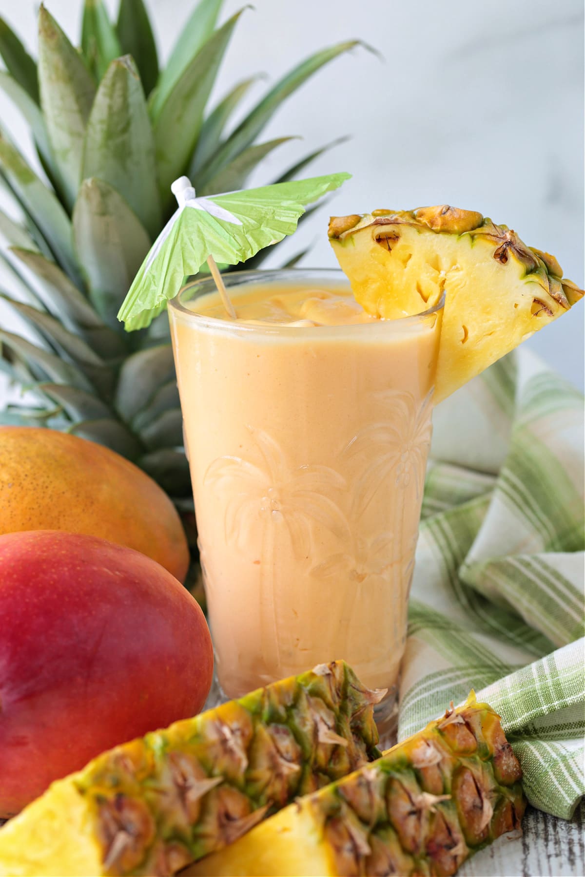 mango pineapple smoothie in glass with umbrella