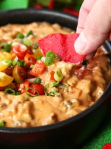 sausage cheese dip in a skillet with tortilla chip dipping in