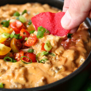 sausage cheese dip in a skillet with tortilla chip dipping in