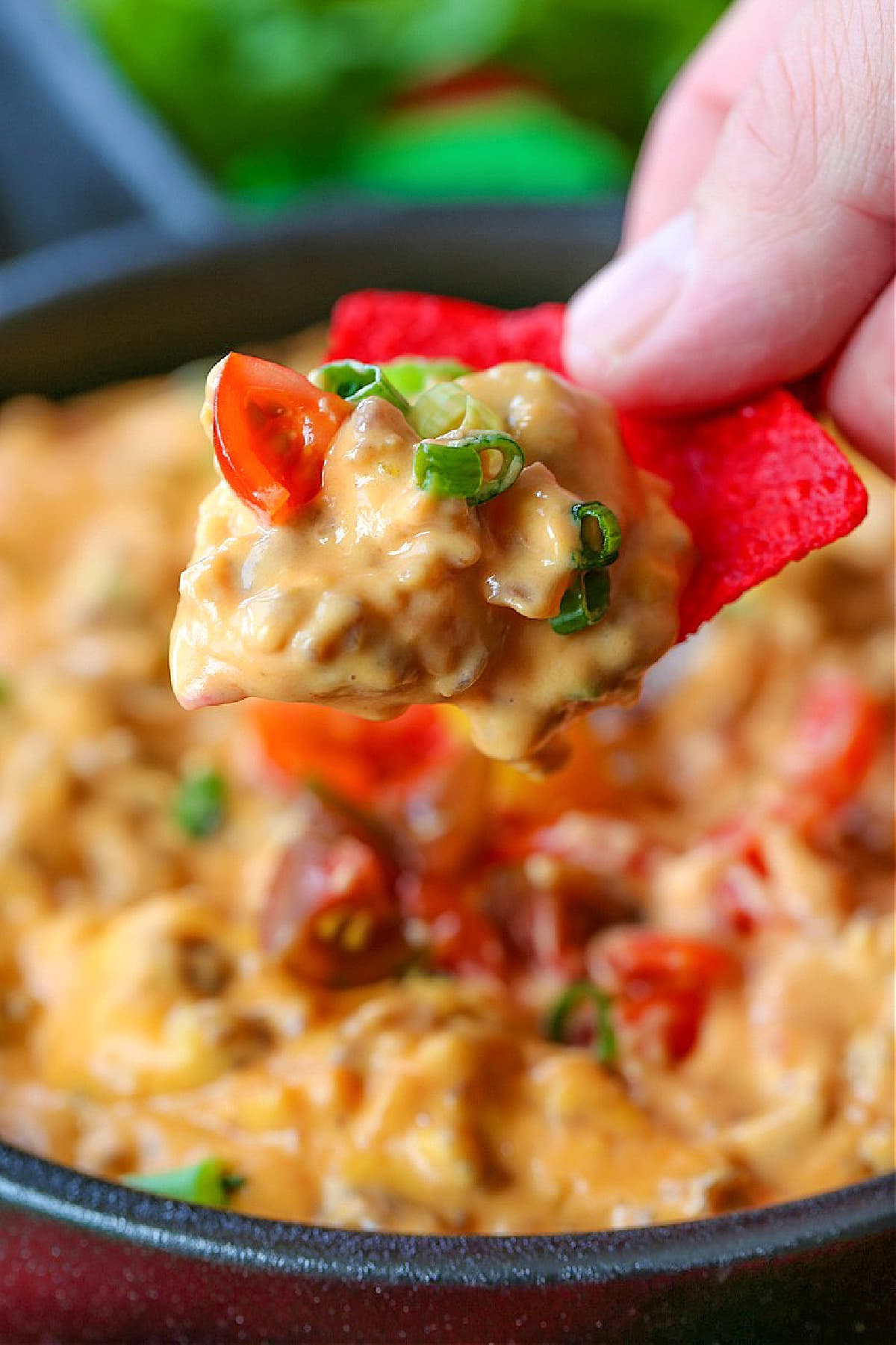 Fiesta Sausage Queso is a favorite appetizer for holidays or parties! An addicting sausage cheese dip made right in your slow cooker! sausage queso on a red tortilla chip