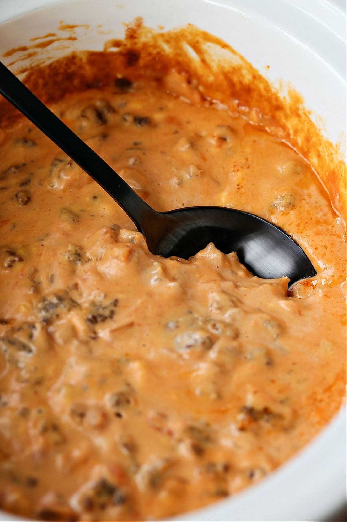 Fiesta Sausage Queso is a favorite appetizer for holidays or parties! An addicting sausage cheese dip made right in your slow cooker! sausage cheese dip in crock pot with spoon