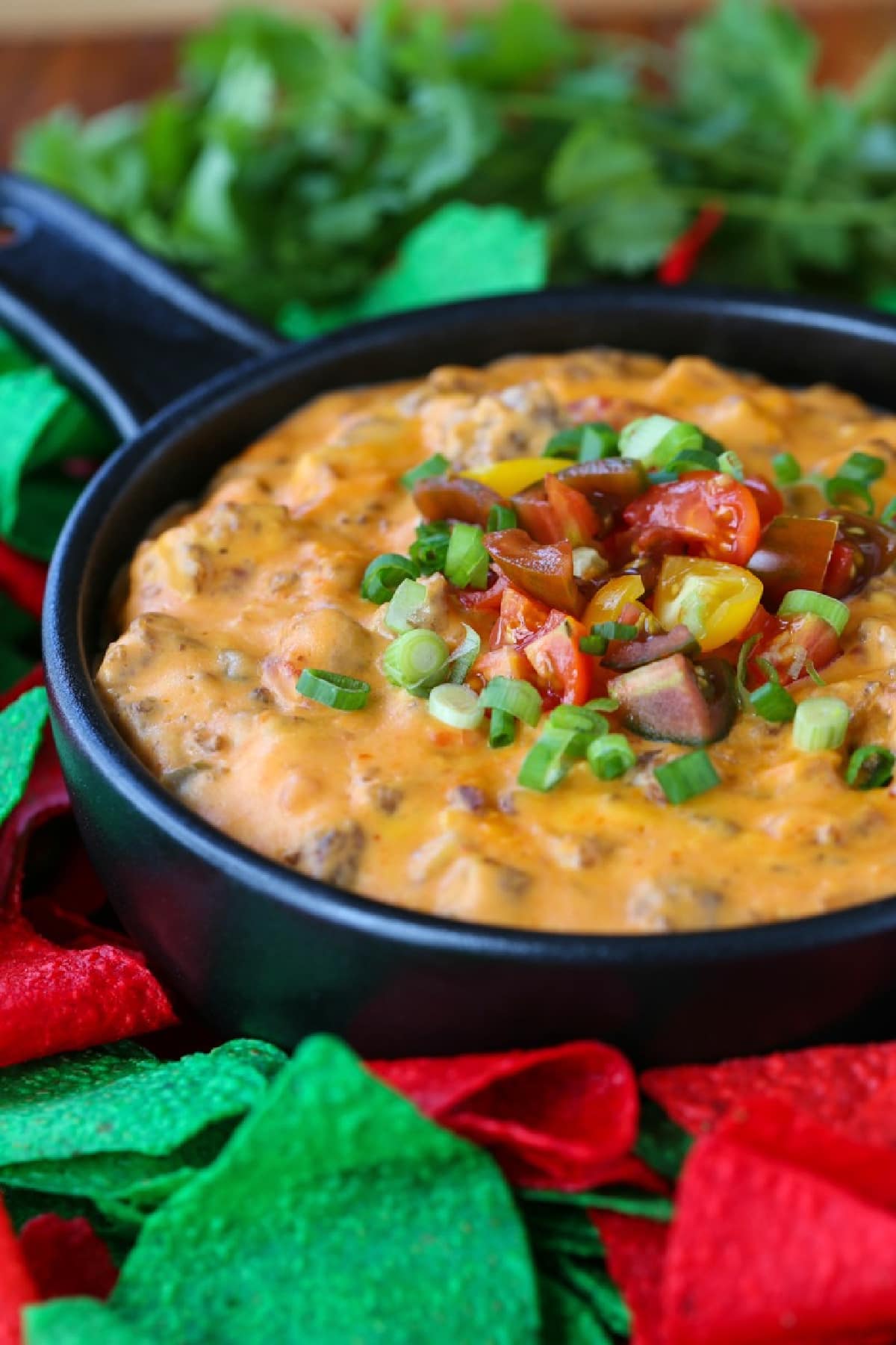 sausage queso in a black skillet with colored tortilla chips