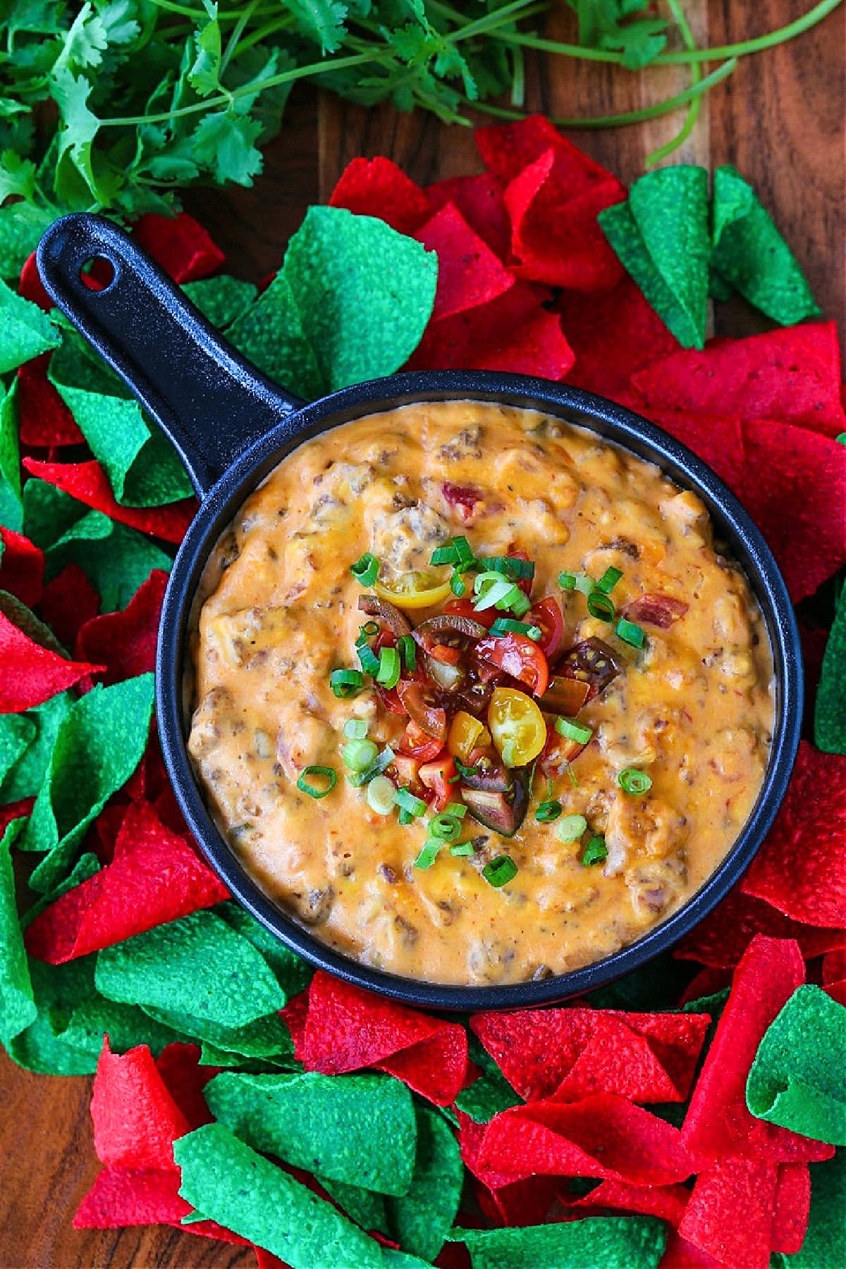 sausage queso in a skillet with colored tortilla chips on the side