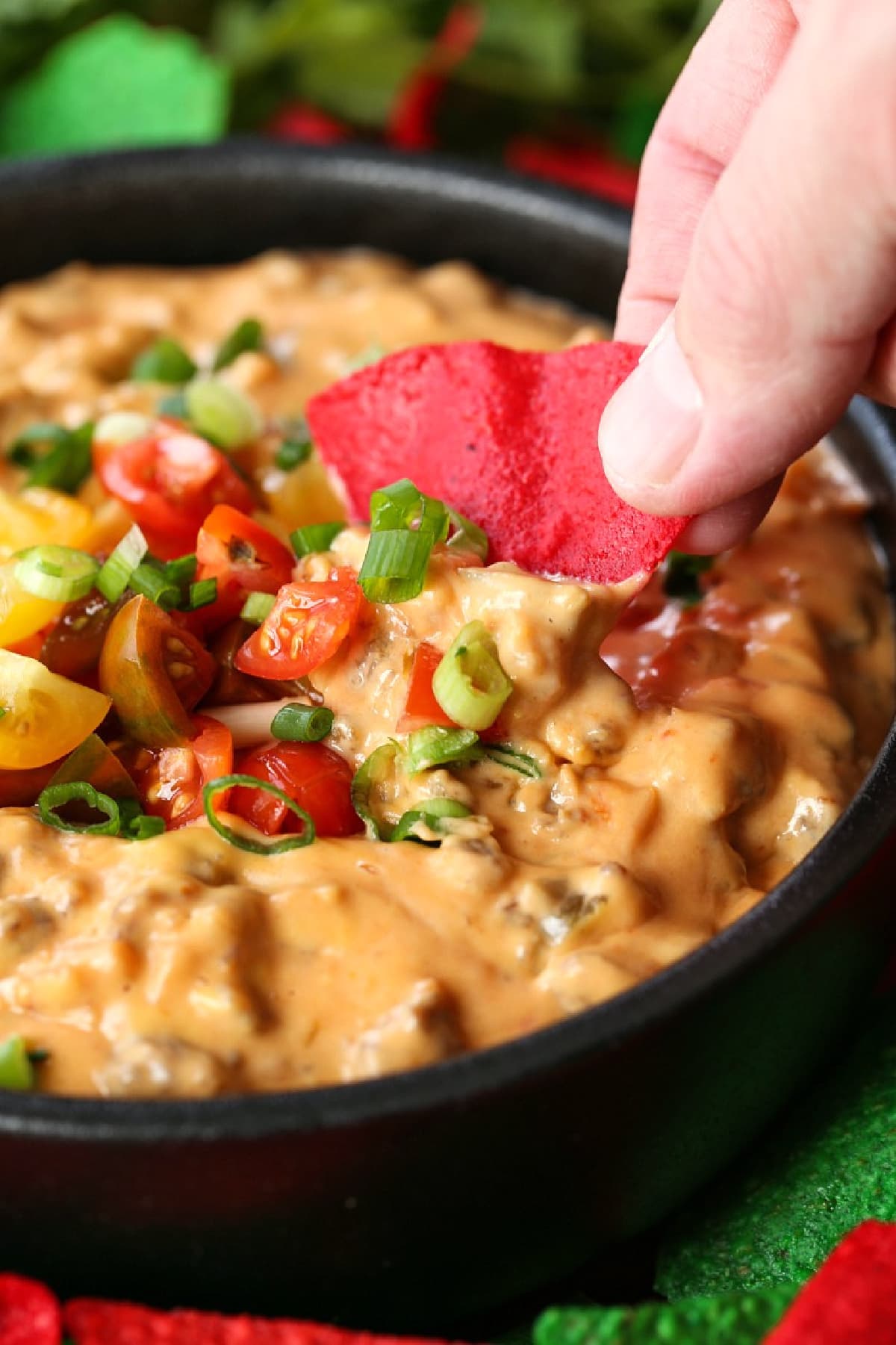 sausage cheese dip in a skillet with tortilla chip dipping in