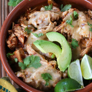 taco chicken in a bowl with sliced avocado and limes