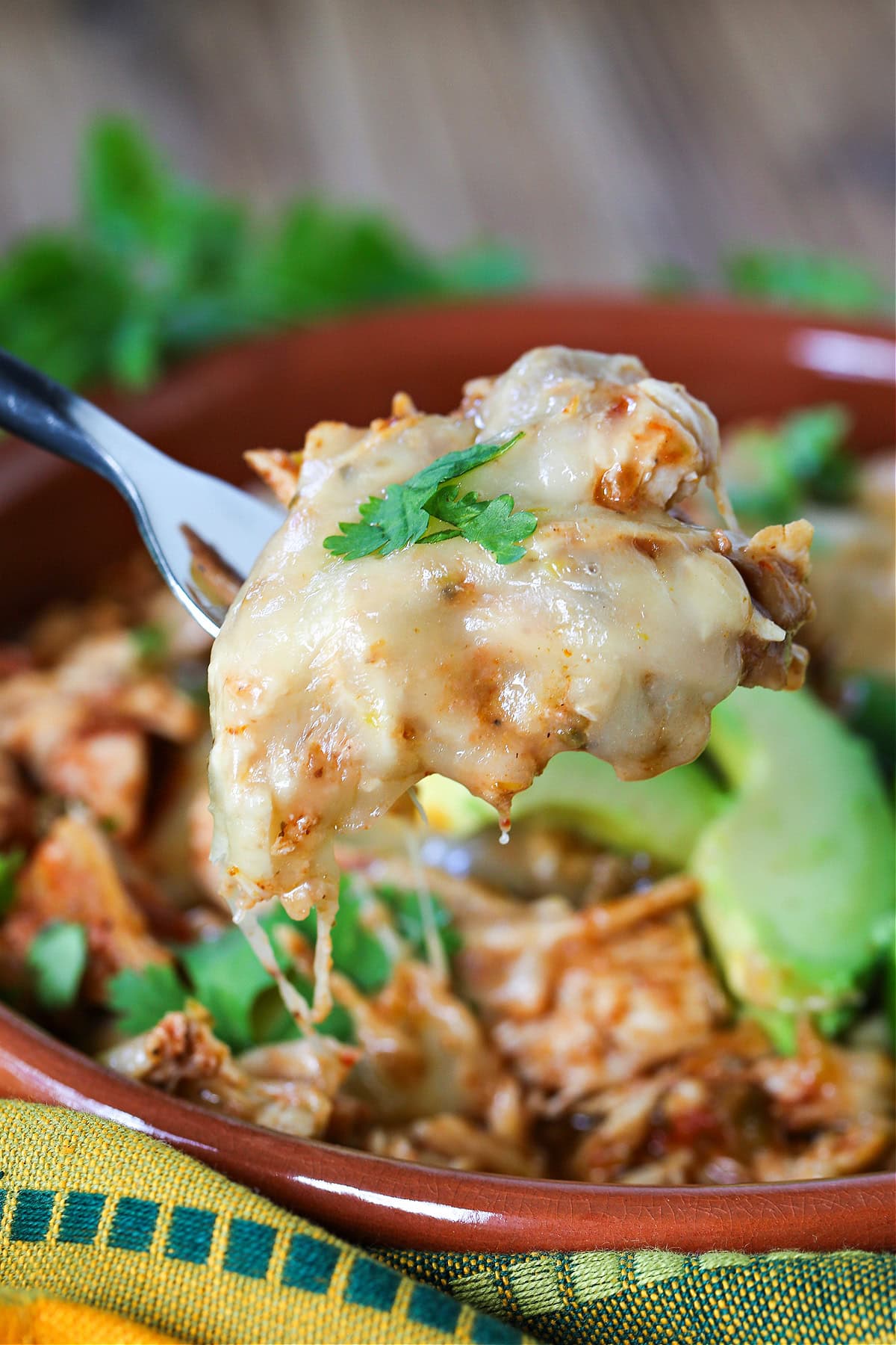 Slow Cooker Taco Chicken is so easy to make. Use it in tacos, rice bowls or on nachos! A slow cooker chicken recipe that everyone loves. fork with bite of taco chicken with cheese
