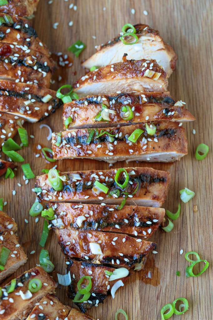 sliced asian chicken on a board with scallions