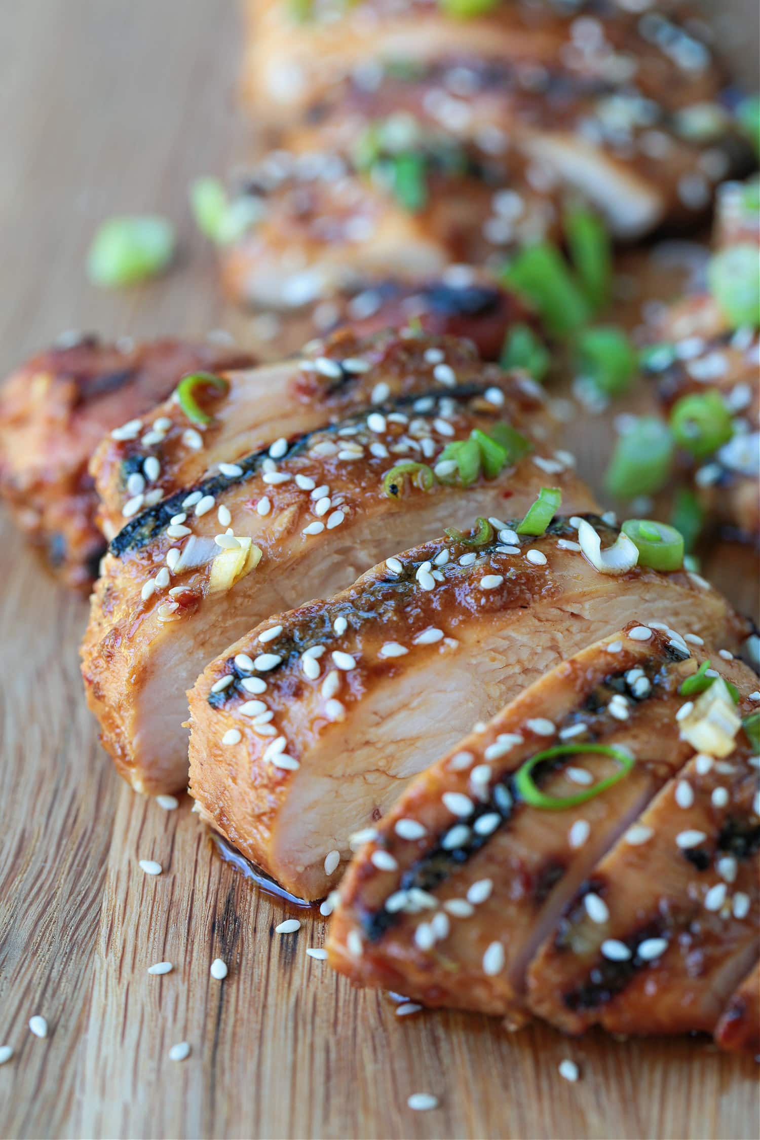 sliced chicken on a board with sesame seeds and scallions