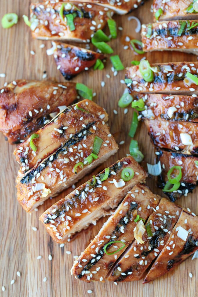sliced asian chicken on a board with scallions