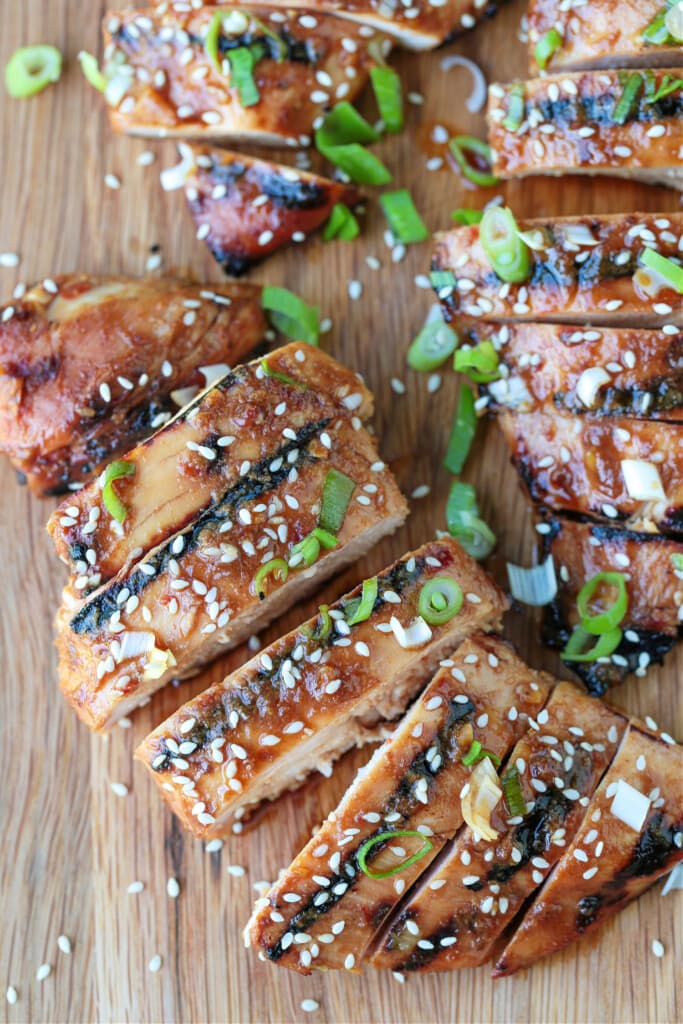 This Asian Chicken Marinade makes the most flavorful chicken! The bright flavors in this marinade will make any chicken delicious and juicy! sliced asian chicken on a board with scallions