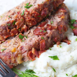 sliced bacon meatloaf on a bed of mashed potatoes