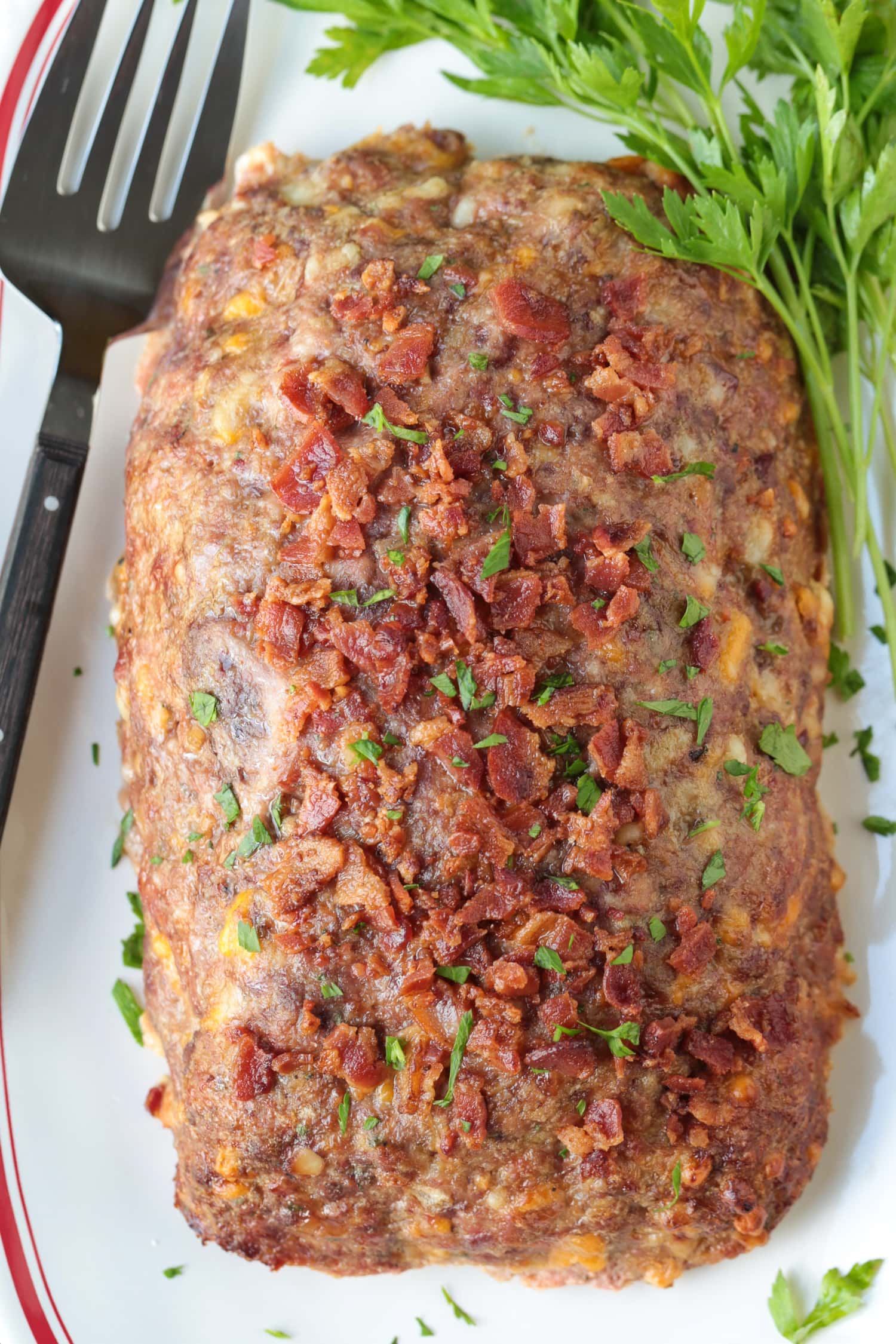 What could be more comforting than a Bacon Meatloaf for dinner? A delicious meatloaf recipe with cheddar cheese and lots of crispy bacon! bacon meatloaf on platter with fork