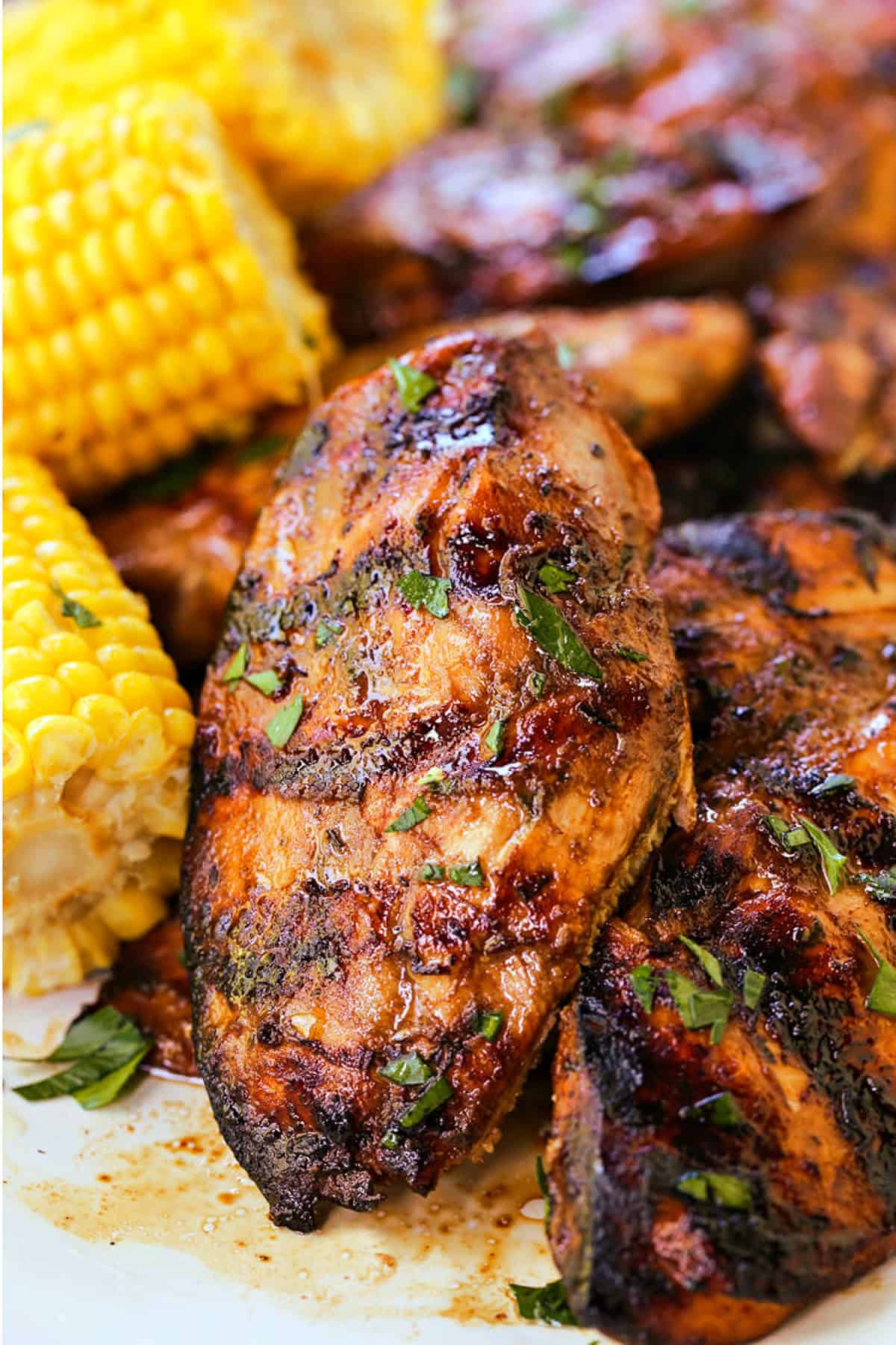 Our Balsamic Chicken Marinade is delicious on any cut of chicken! Tangy and sweet with fresh, vibrant herbs that flavor chicken wonderfully. grilled balsamic chicken breasts stacked on a platter with corn