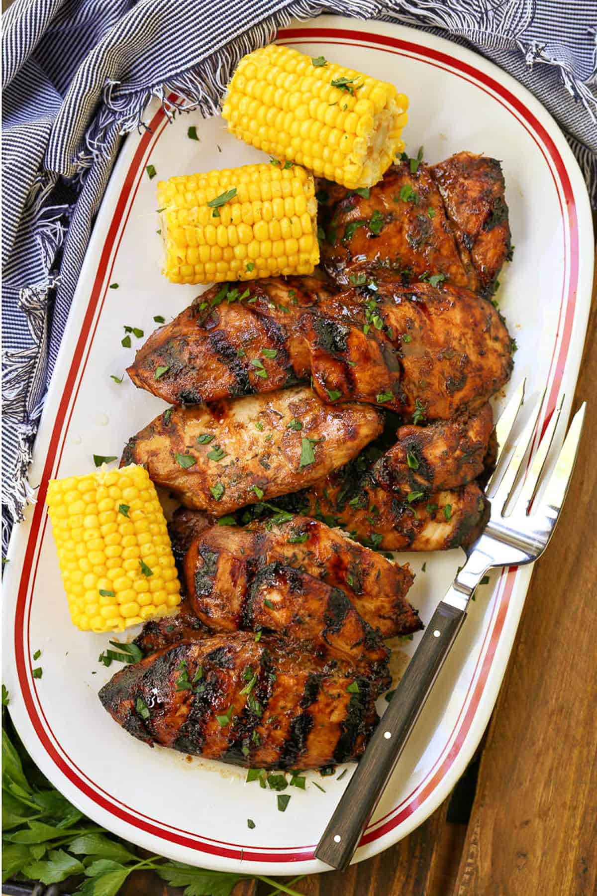 Our Balsamic Chicken Marinade is delicious on any cut of chicken! Tangy and sweet with fresh, vibrant herbs that flavor chicken wonderfully. grilled chicken breasts on a serving platter with corn and fork