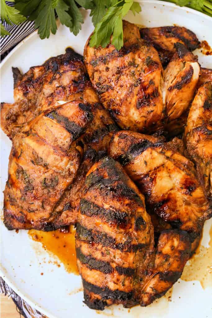 Our Balsamic Chicken Marinade is delicious on any cut of chicken! Tangy and sweet with fresh, vibrant herbs that flavor chicken wonderfully. grilled, marinated chicken breasts on a plate with juices