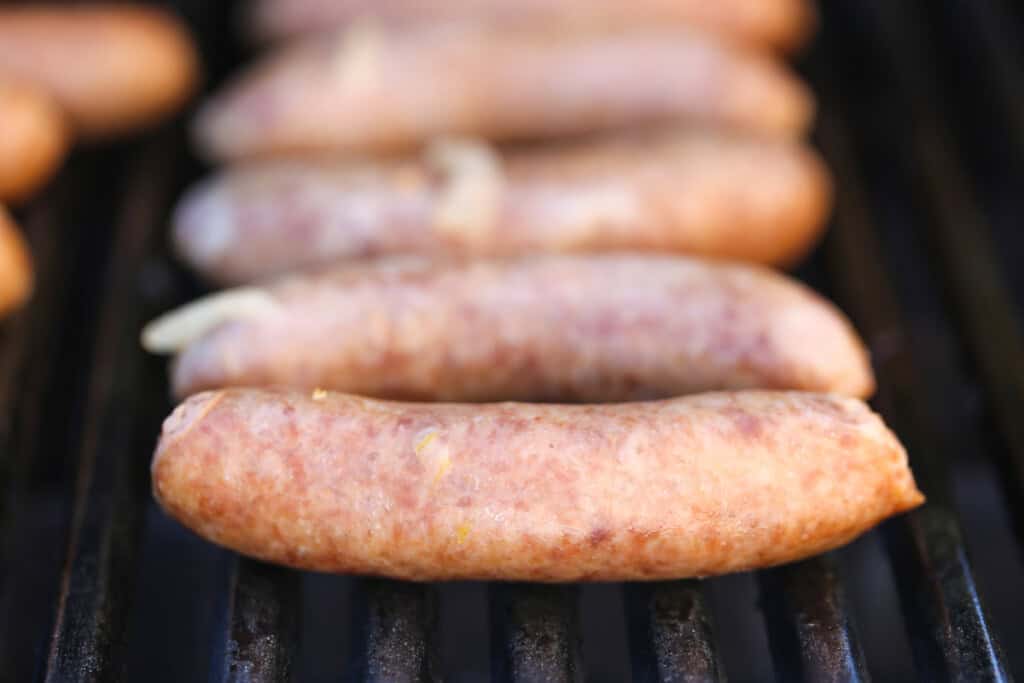 Beer Brats are a family favorite! Bratwurst cooked in beer, onions and our secret ingredient that makes them super tender and flavorful! bratwurst on grill