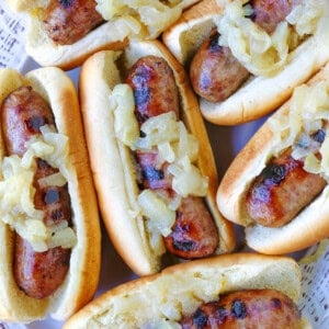 bratwurst with onions on buns on platter