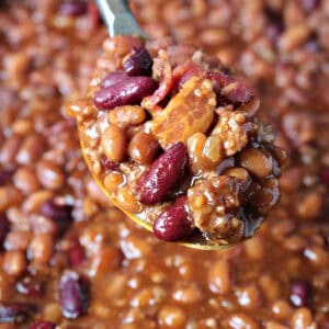 baked beans with ground beef and bacon on serving spoon
