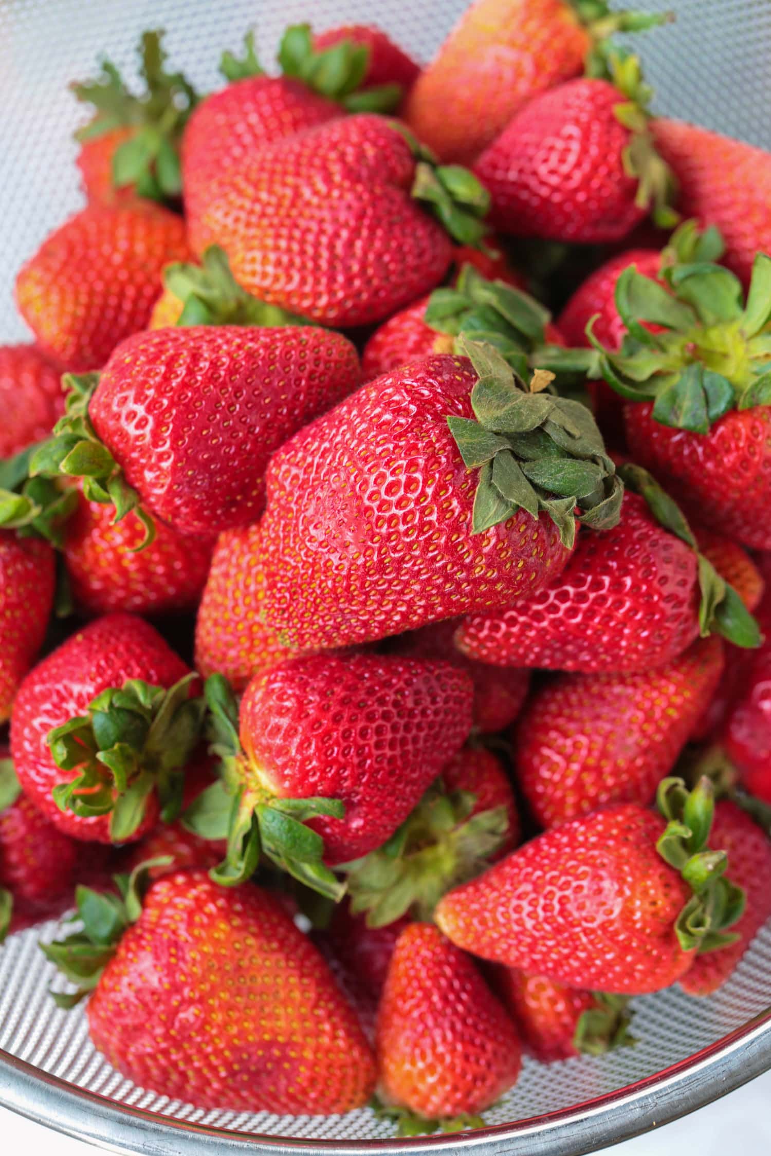 Strawberry Compote is an such an easy dessert to make! Just three ingredients turn into this sweet, addicting sauce for ice cream and more! fresh strawberries in a colander