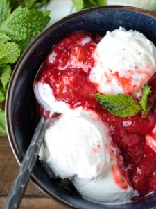 strawberry compote poured over ice cream with a spoon