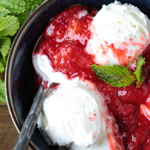 strawberry compote poured over ice cream with a spoon