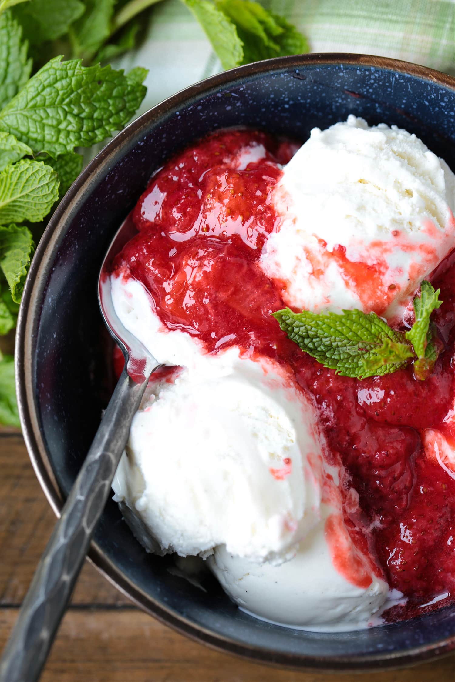 strawberry compote poured over ice cream with a spoon