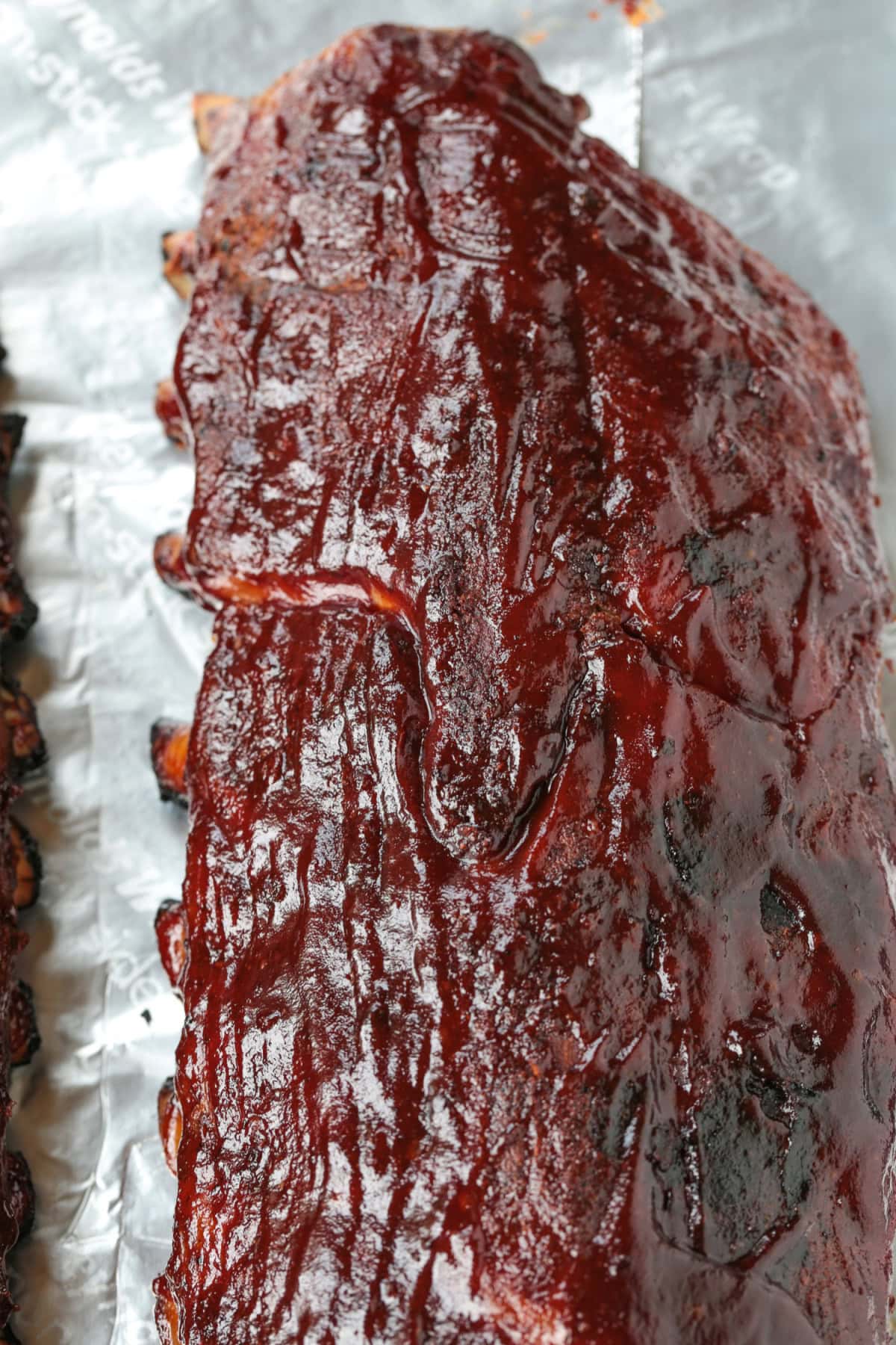The BEST BBQ Ribs Recipe for easy dinner nights and parties! Seasoned with our signature dry rub, they're perfectly tender and so addicting. slab of barbecue ribs on foil