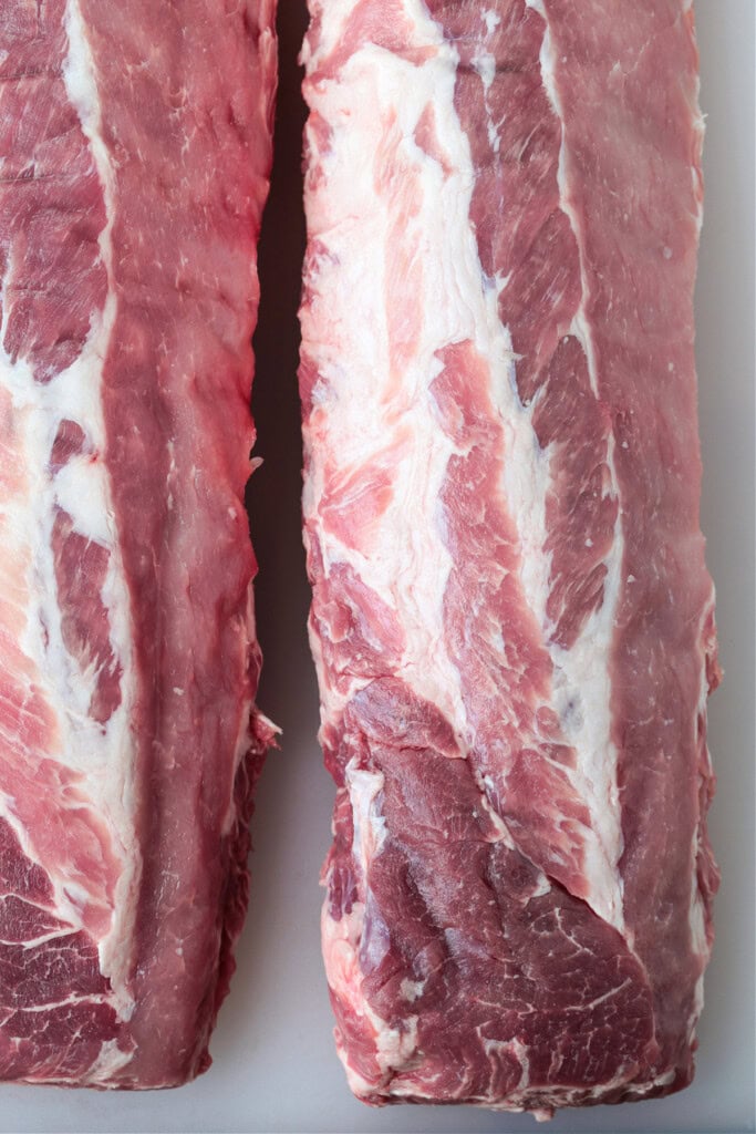 The BEST BBQ Ribs Recipe for easy dinner nights and parties! Seasoned with our signature dry rub, they're perfectly tender and so addicting. two raw racks of ribs on foil
