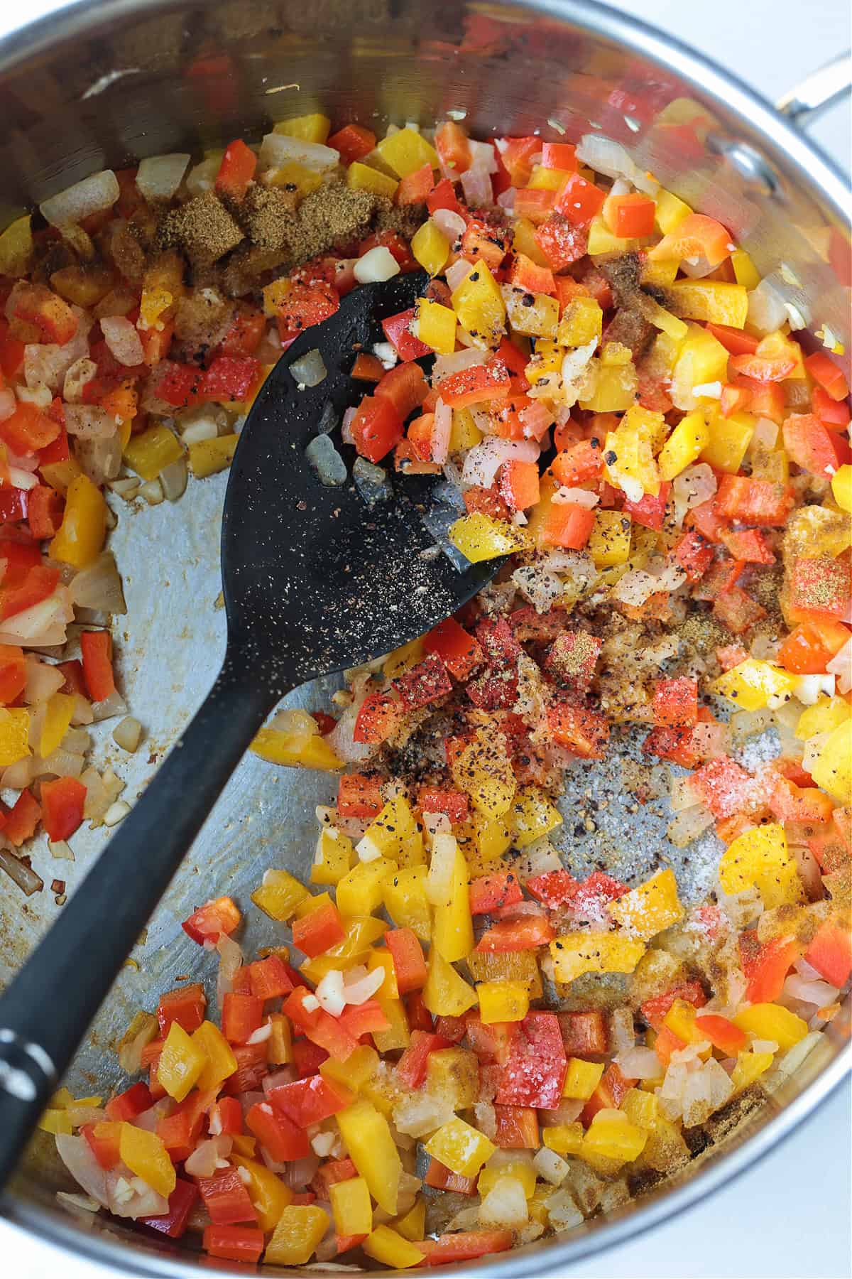 Our Chicken Fajita Soup is packed with protein! A secret ingredient makes this soup thick and creamy, without any cream or cream cheese! peppers and onions cooking in a pot with spoon