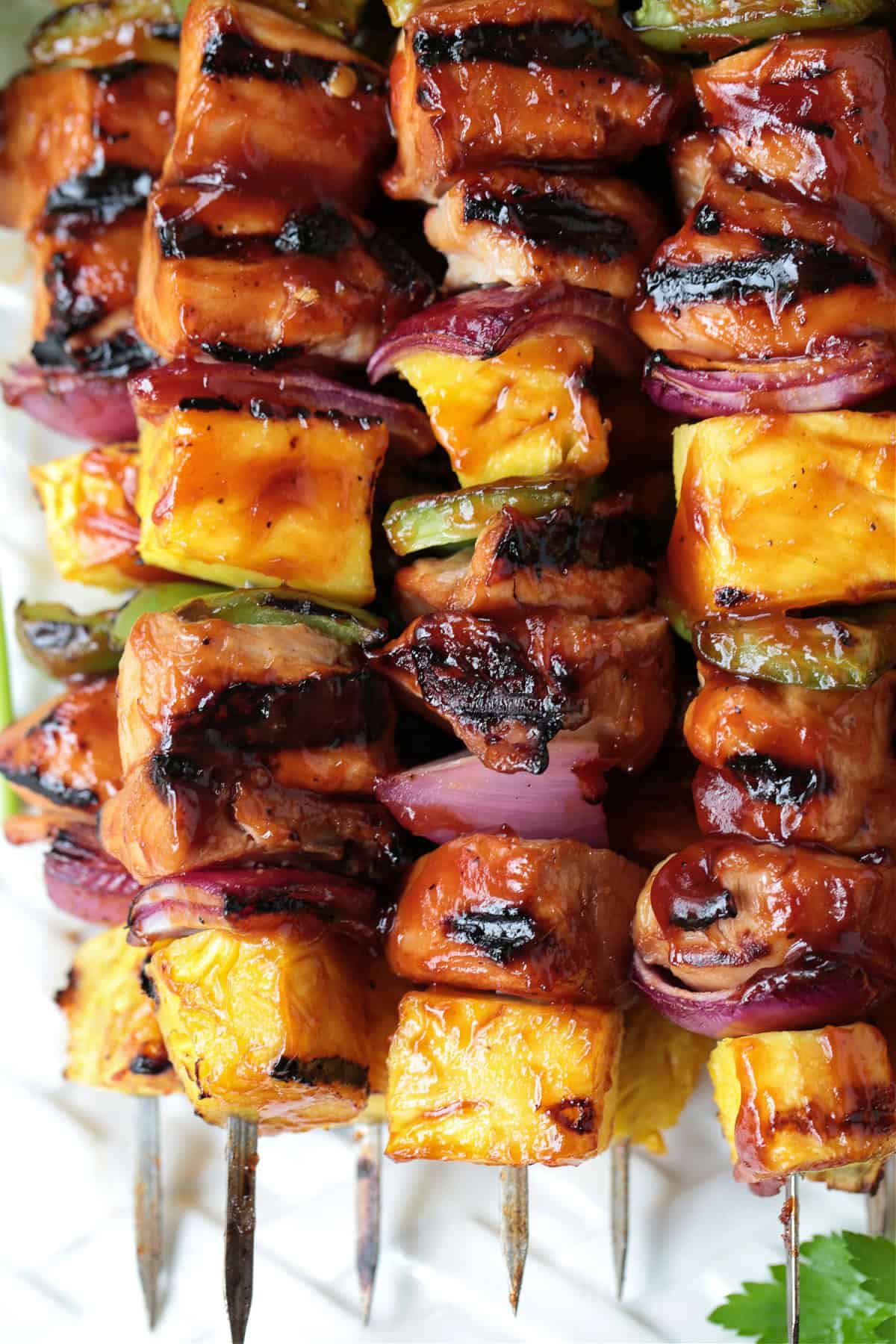 Chicken Pineapple Kabobs are a fun and tasty dinner! Sweet, grilled pineapple combined with juicy, marinated chicken and roasted vegetables. close up of chicken and pineapple kabobs on skewers