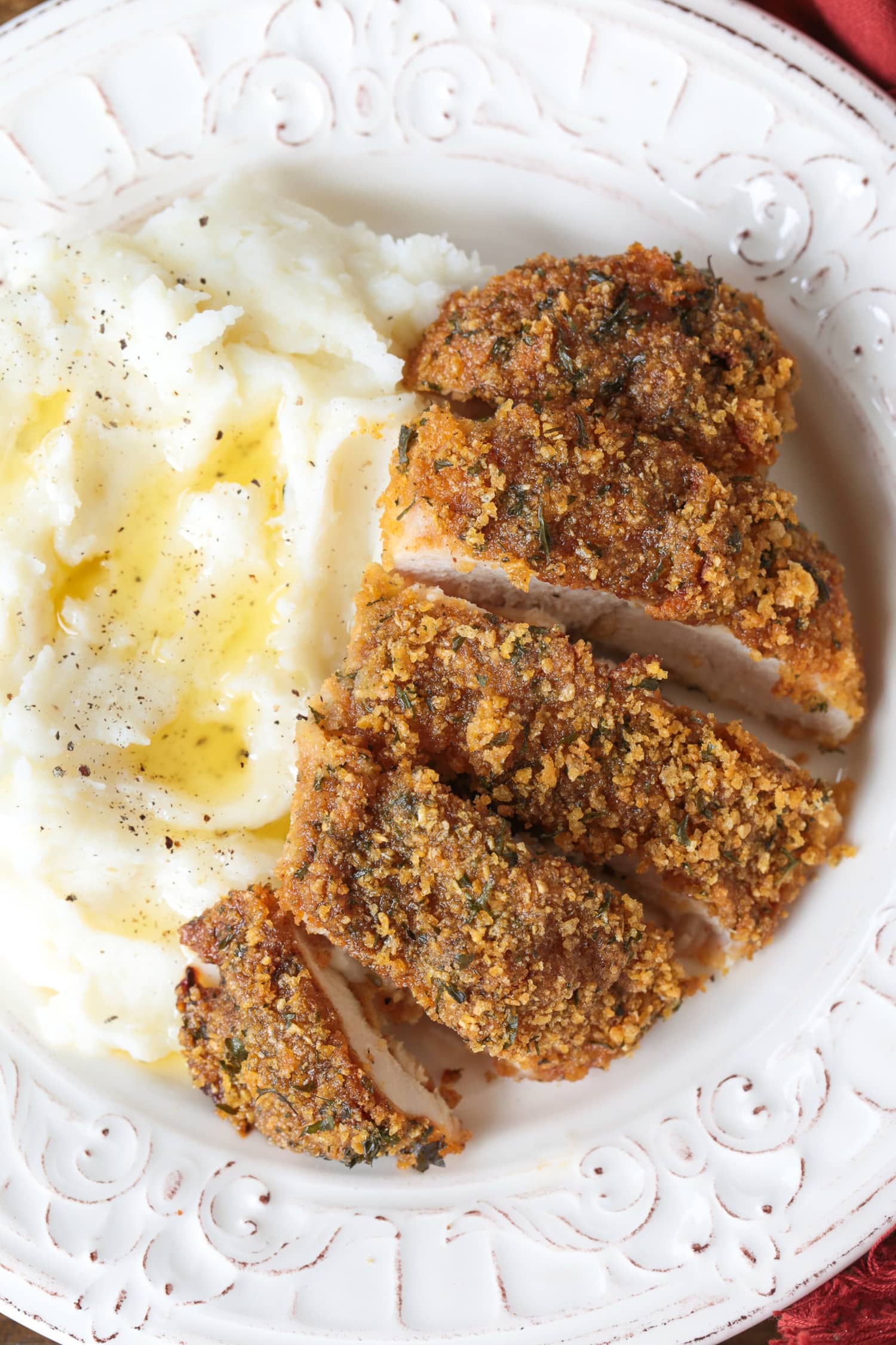 cornflake chicken sliced on plate with potatoes