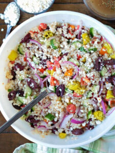 greek couscous salad in bowl with feta and dressing on side
