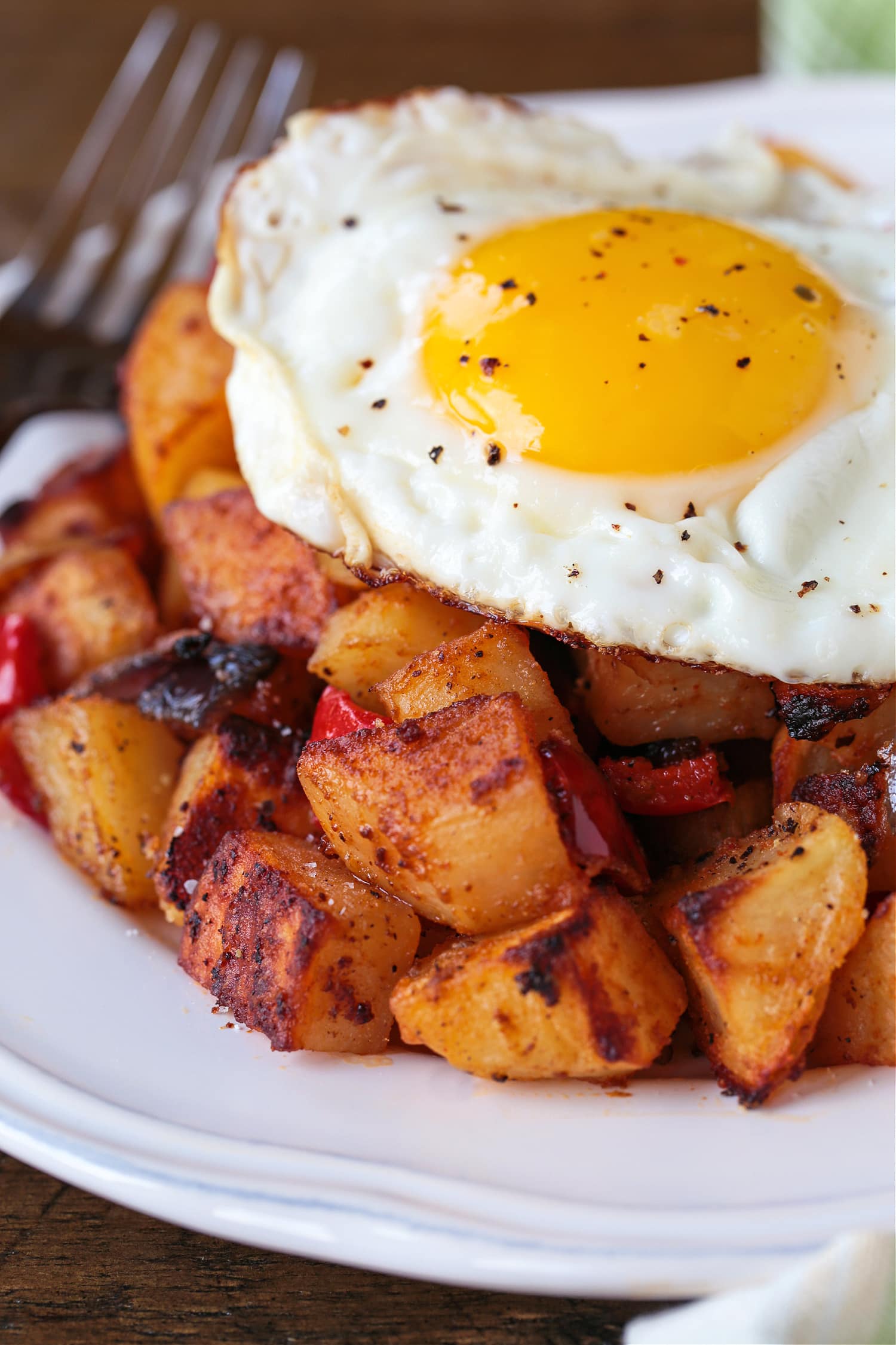 These Breakfast Potatoes are deliciously seasoned and roasted to a crispy perfection! A tasty side dish for breakfast, brunch or dinner! fried egg on a bed of breakfast potatoes