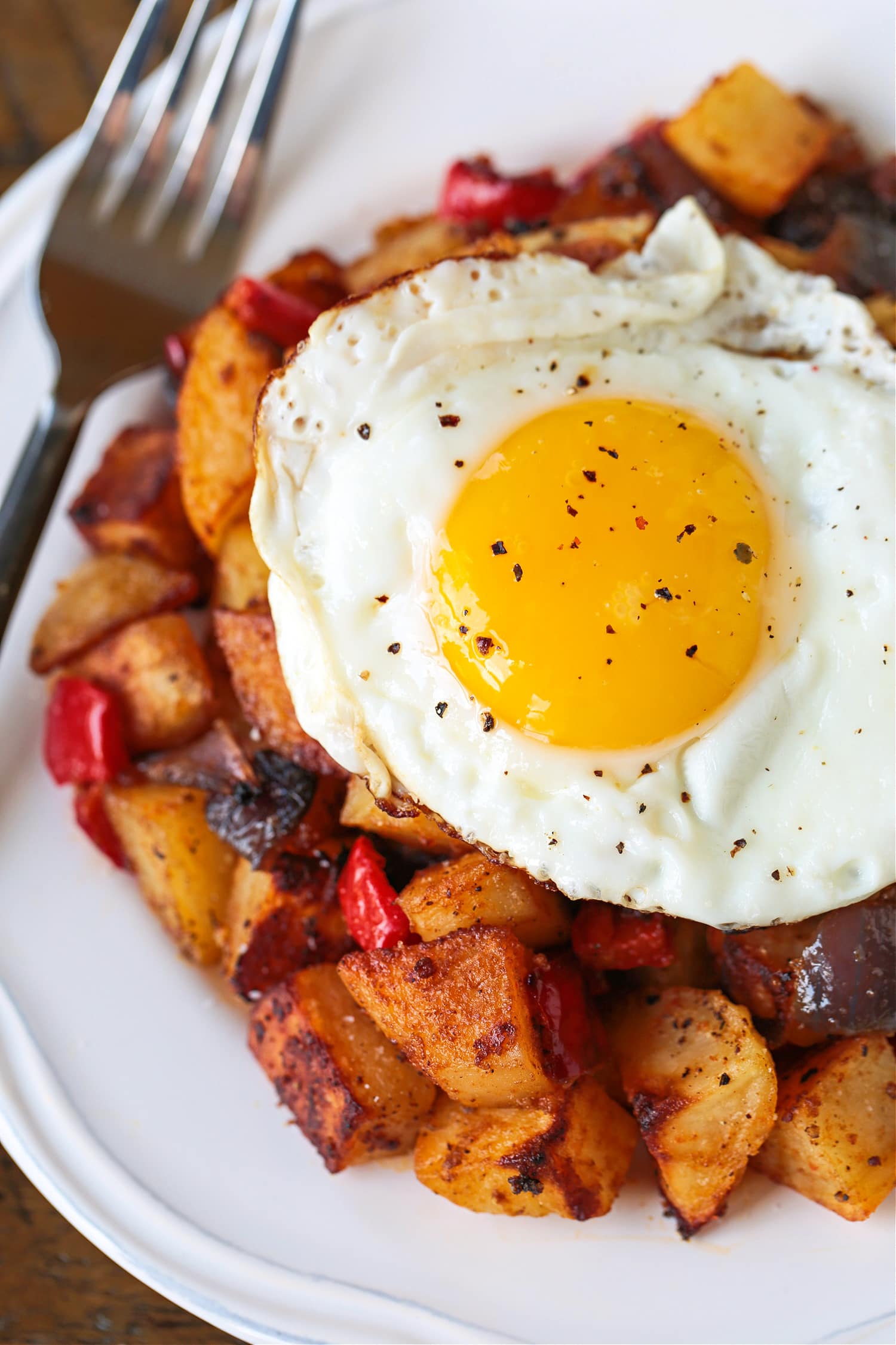 These Crispy Breakfast Potatoes are perfectly seasoned and roasted to perfection. A tasty side dish for breakfast, brunch or dinner! fried egg on top of breakfast potatoes